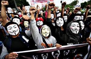 Filipino student protesters wearing masks raise their clenched fist as they pass by the gates of the House of Representatives in suburban Quezon city, north of Manila, Philippines on Tuesday Nov. 5, 2013. Supporters of hacker group Anonymous Philippines held the rally to call for the abolition of all forms of "pork barrel" funds after allegations that several members of the House of Representatives and the Philippine Senate conspired with wealthy businesswoman Janet Lim Napoles to steal huge amounts of government development funds. Napoles is set to appear before the Senate Blue Ribbon Committee on Nov. 7. (AP Photo/Aaron Favila)